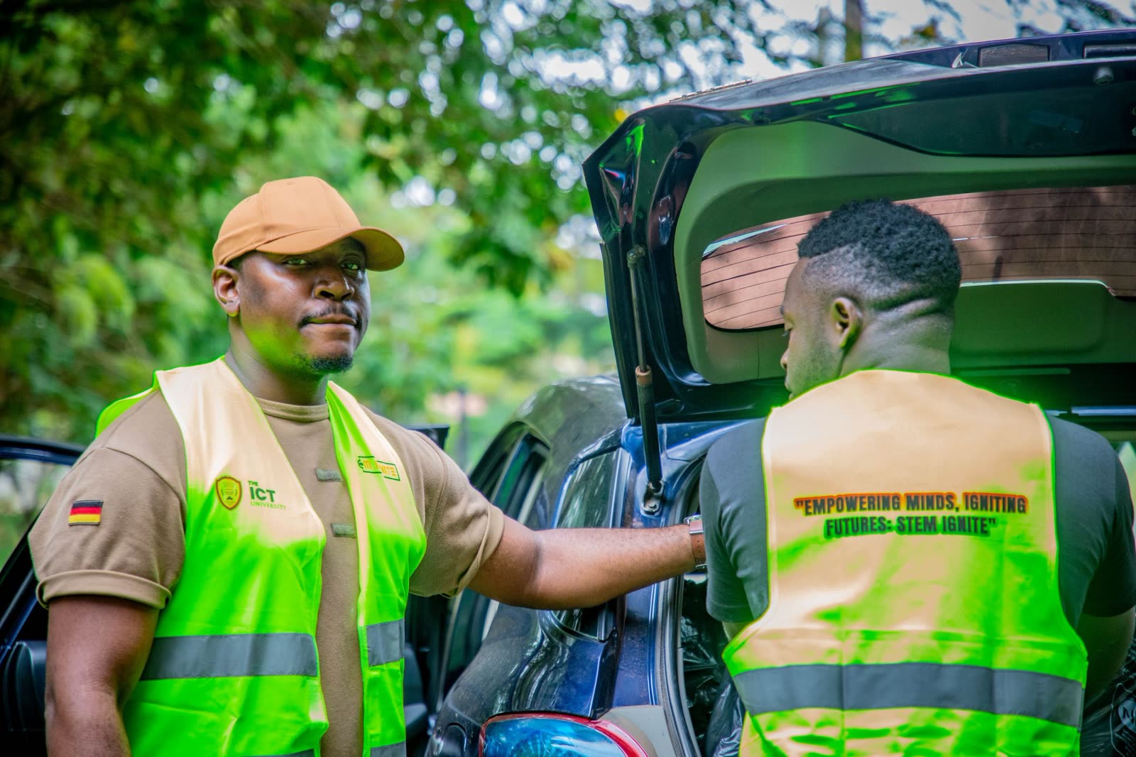 Emmanuel Fru and a colleague in high-visibility STEM Ignite vests beside a car